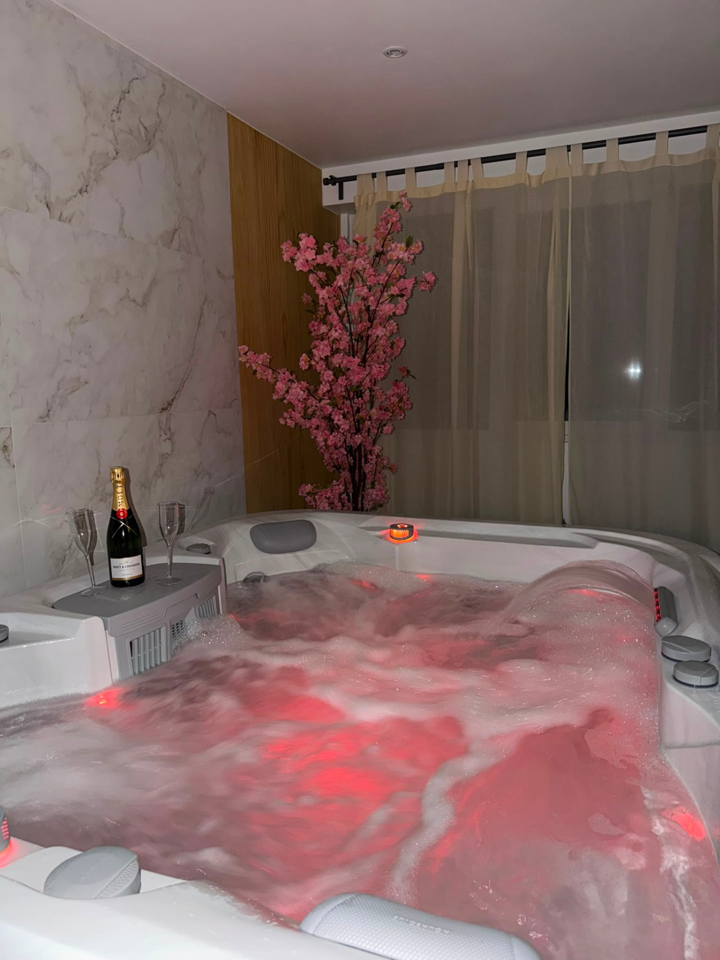 Spa de la suite à Chimay, eau éclairée en rose et décor de cerisier
